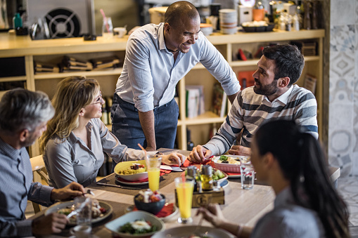 Restaurant manager engaging warmly with guests at the table
