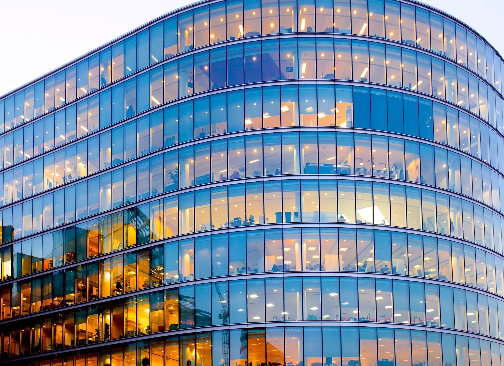 Large corporate office building with many lit workspaces